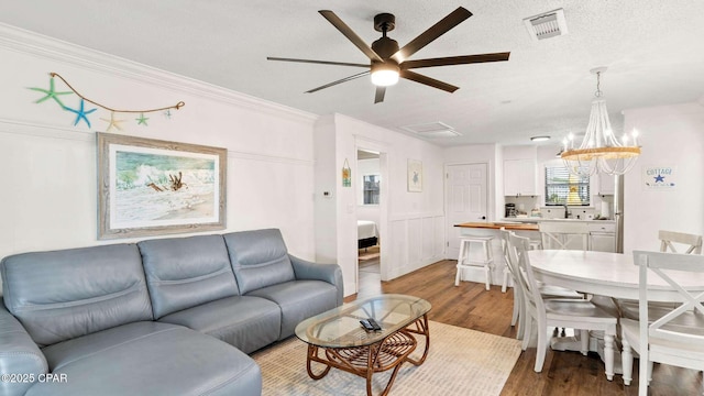 living room with ceiling fan, ornamental molding, light hardwood / wood-style flooring, and a textured ceiling