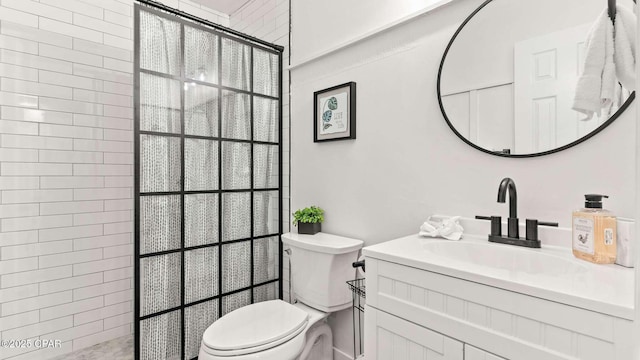 bathroom with vanity, toilet, and tiled shower