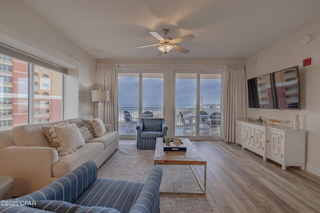 living room with ceiling fan, a healthy amount of sunlight, and light wood-type flooring