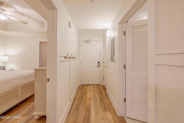 corridor featuring a textured ceiling and light wood-type flooring