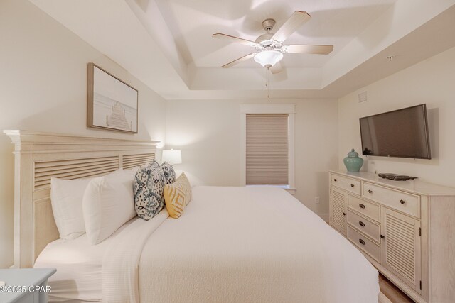 bedroom with ceiling fan and a tray ceiling