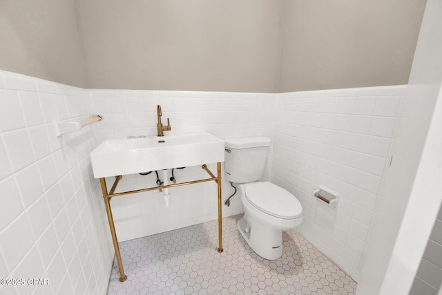 bathroom featuring toilet, sink, and tile walls