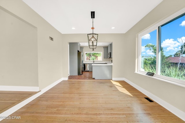 unfurnished living room featuring sink and light hardwood / wood-style flooring