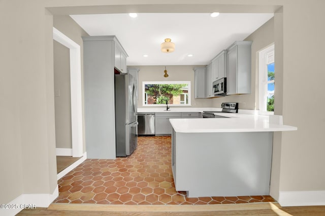 kitchen featuring gray cabinetry, sink, kitchen peninsula, and appliances with stainless steel finishes