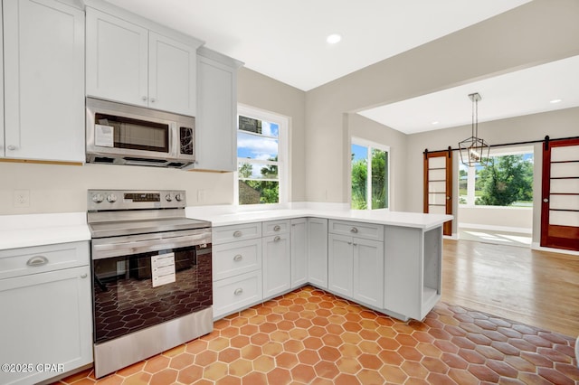 kitchen with decorative light fixtures, appliances with stainless steel finishes, a healthy amount of sunlight, and kitchen peninsula