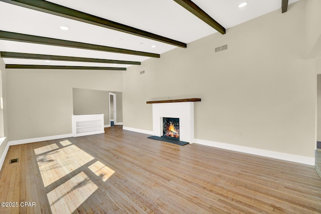 unfurnished living room featuring vaulted ceiling with beams and light hardwood / wood-style floors