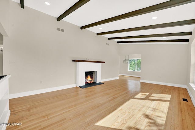 unfurnished living room featuring vaulted ceiling with beams and wood-type flooring