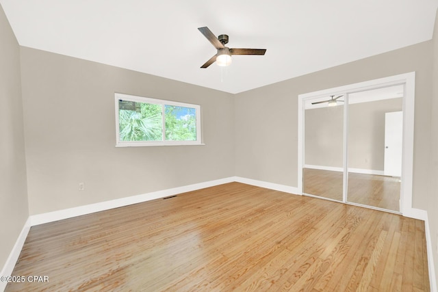 unfurnished bedroom with ceiling fan, a closet, and light wood-type flooring