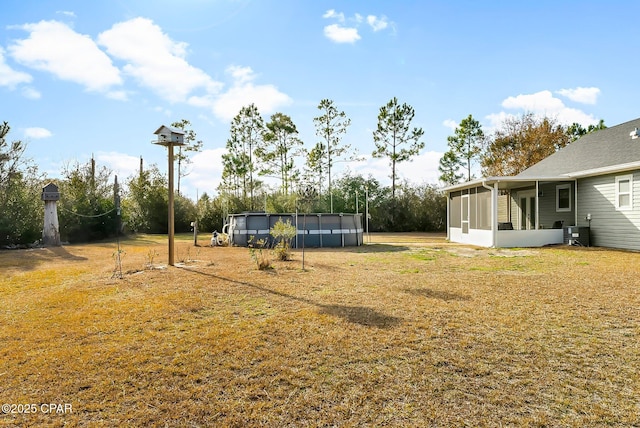 view of yard with central air condition unit, a sunroom, and an outdoor pool