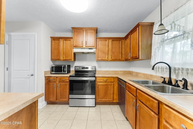 kitchen featuring decorative light fixtures, light countertops, appliances with stainless steel finishes, a sink, and under cabinet range hood