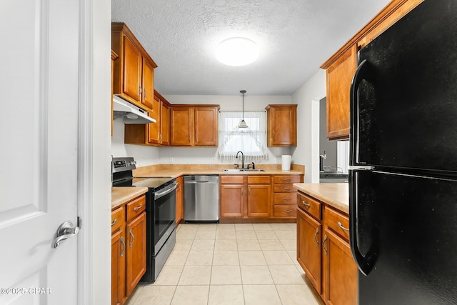 kitchen with under cabinet range hood, a sink, light countertops, appliances with stainless steel finishes, and decorative light fixtures