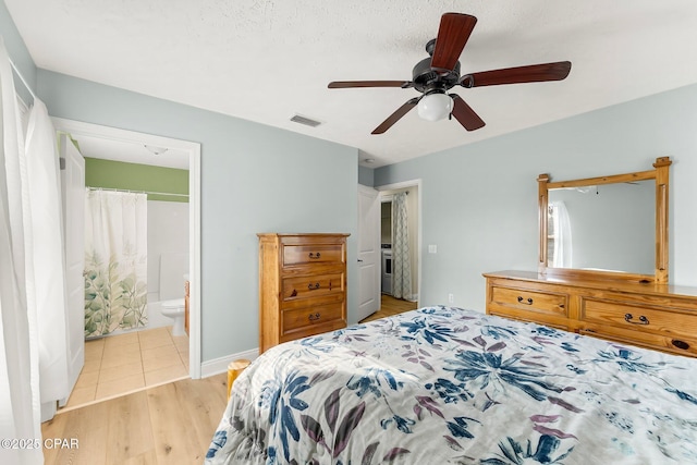 bedroom featuring visible vents, baseboards, ensuite bath, ceiling fan, and light wood-style floors