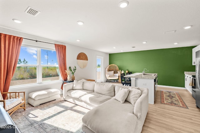living room featuring sink and light hardwood / wood-style flooring