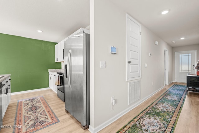 kitchen with white cabinetry, stainless steel appliances, and light wood-type flooring