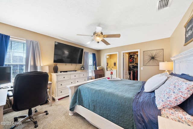 carpeted bedroom featuring ceiling fan, a spacious closet, a closet, and a textured ceiling