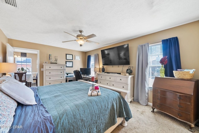 carpeted bedroom featuring ceiling fan and a textured ceiling