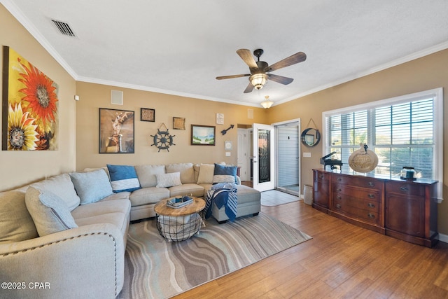 living room with light hardwood / wood-style flooring, ornamental molding, and ceiling fan