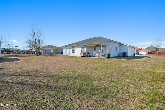 back of house with central AC unit and a yard