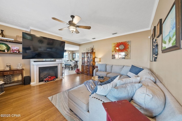 living room with ornamental molding, ceiling fan, and light hardwood / wood-style flooring