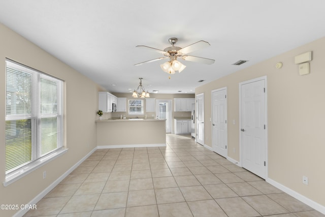 unfurnished living room featuring light tile patterned flooring and ceiling fan with notable chandelier