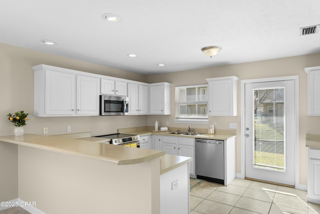 kitchen featuring stainless steel appliances, white cabinetry, sink, and kitchen peninsula