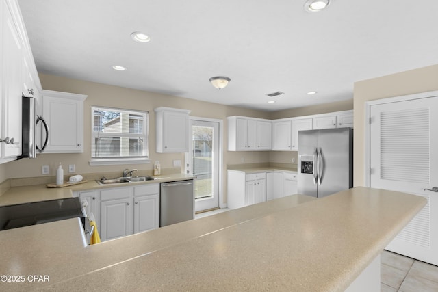 kitchen with light tile patterned floors, appliances with stainless steel finishes, sink, and white cabinets