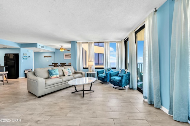 living area featuring floor to ceiling windows, visible vents, ceiling fan, a textured ceiling, and baseboards