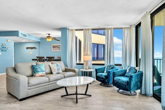 living area with a healthy amount of sunlight, visible vents, a textured ceiling, and wood finished floors