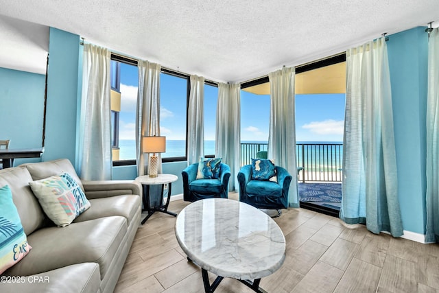 living area featuring a water view, baseboards, a wealth of natural light, and wood finish floors