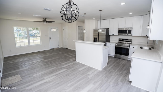 kitchen featuring pendant lighting, white cabinets, a center island, light hardwood / wood-style floors, and stainless steel appliances