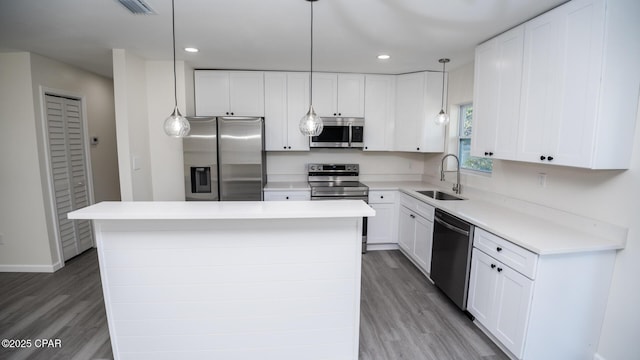 kitchen with white cabinetry, appliances with stainless steel finishes, sink, and a kitchen island