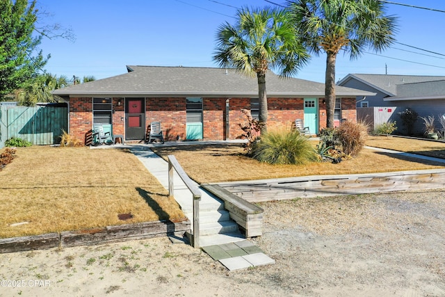 single story home featuring fence, brick siding, and roof with shingles