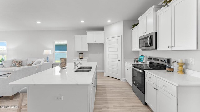 kitchen featuring recessed lighting, a sink, white cabinetry, open floor plan, and appliances with stainless steel finishes