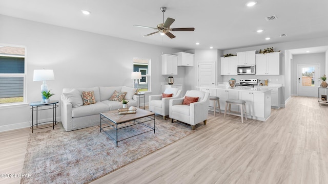 living area featuring light wood finished floors, baseboards, visible vents, and recessed lighting