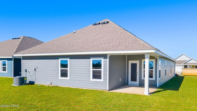 rear view of house featuring a shingled roof, cooling unit, a lawn, and a patio