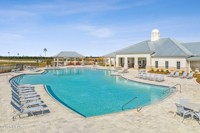 community pool with a patio area, fence, and a gazebo