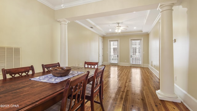 dining room with wood-type flooring, visible vents, a ceiling fan, ornamental molding, and ornate columns