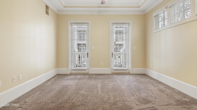 carpeted empty room featuring baseboards, a tray ceiling, and crown molding