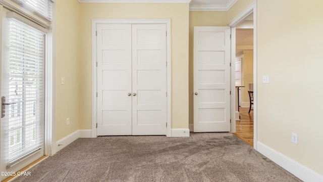 unfurnished bedroom with baseboards, carpet, ornamental molding, and a closet