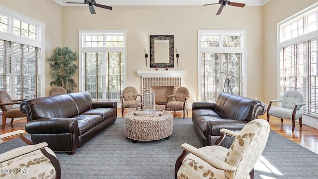 living room with a fireplace, wood finished floors, a wealth of natural light, and a ceiling fan