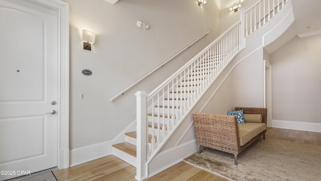 staircase featuring a high ceiling, baseboards, and wood finished floors