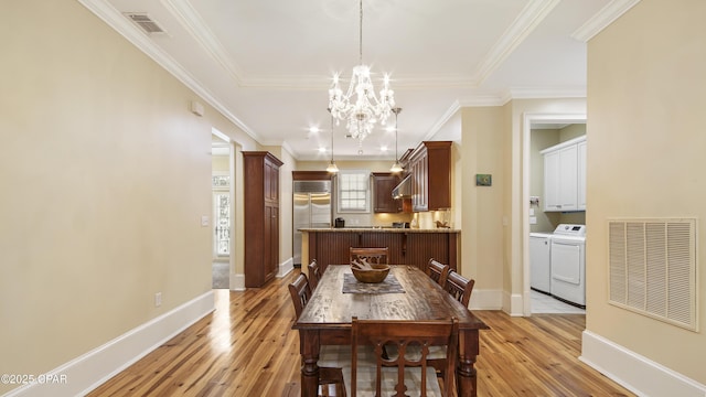 dining room featuring light wood finished floors, baseboards, visible vents, independent washer and dryer, and a chandelier