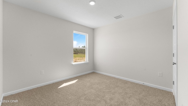 carpeted empty room with visible vents and baseboards