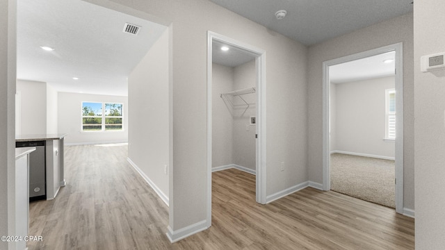 corridor featuring light wood-style flooring, visible vents, and baseboards