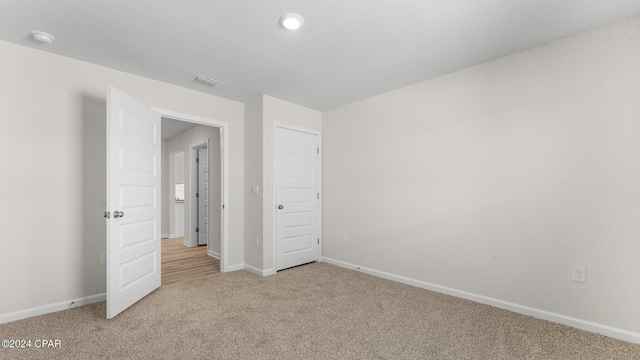 unfurnished bedroom featuring baseboards, visible vents, and light colored carpet