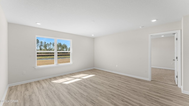 empty room featuring recessed lighting, light wood-style flooring, and baseboards