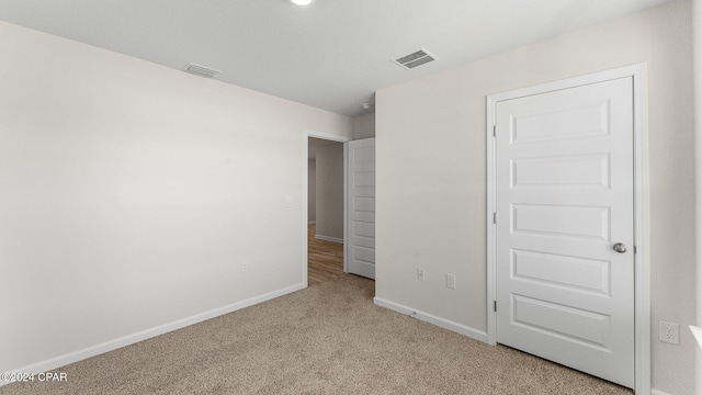 unfurnished bedroom featuring visible vents, light carpet, and baseboards