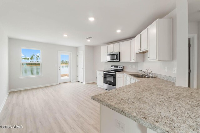 kitchen featuring appliances with stainless steel finishes, light stone countertops, sink, and white cabinets