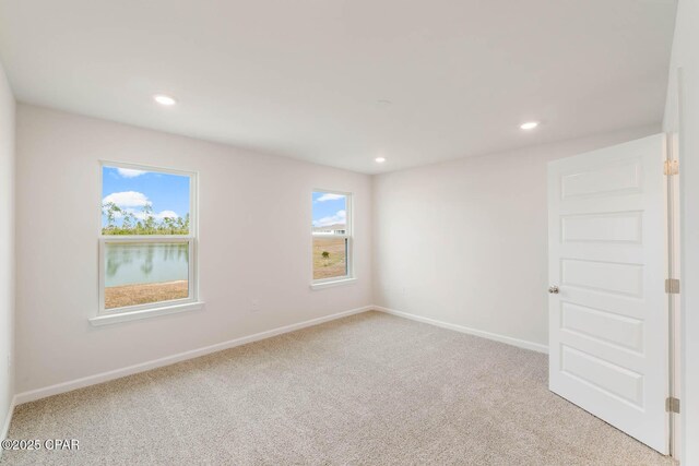 unfurnished room featuring light colored carpet and a water view