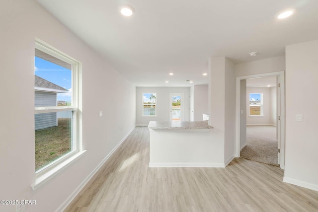 kitchen featuring a wealth of natural light, light hardwood / wood-style flooring, and light stone countertops